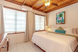 Una habitación de hotel con una cama, un escritorio y un ventilador de techo.