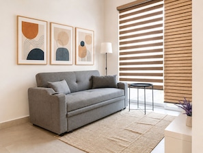 A modern living room with a grey sofa, a floor lamp, and abstract wall art.