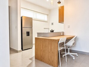 A modern kitchen with a built-in island, stainless steel refrigerator, and white cabinetry. - JC6 Executive Loft L1 in Pueblo Nuevo, Corregidora (El Pueblito)