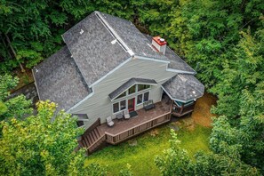 Ein zweistöckiges Haus mit Veranda und überdachter Terrasse, umgeben von dichtem Grün.