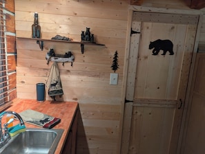 A wooden interior with a kitchen sink, a towel, and a bear decoration on the wall.