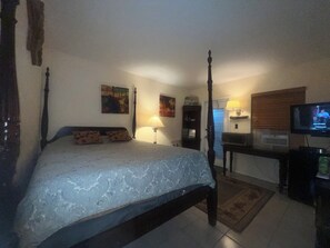 A four-poster bed with a patterned bedspread, a television on a stand, and artwork on the walls. - Charming BEACH apartment in Fabulous Lauderdale-by-the-Sea (Lauderdale-by-the-Sea)