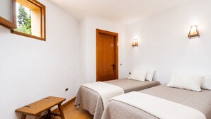 A room with two beds, a wooden door, a small table, and a window. - Home2Book Icod Terrace, BBQ & Nature (Icod de los Vinos)