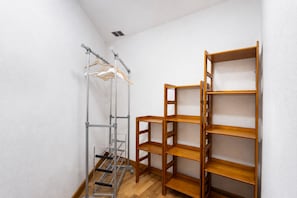 Een hoek van een kamer met een metalen droogrek en houten planken.