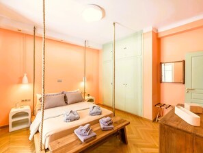 Une chambre comprenant un lit, une table de chevet, des lampes suspendues, une armoire et un miroir.