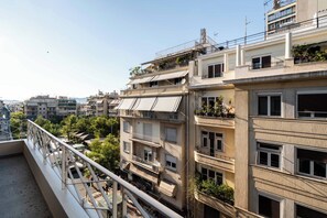 Un immeuble résidentiel à plusieurs étages, doté de balcons, d’une promenade piétonne et surplombant un ciel dégagé.