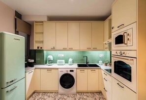 A compact kitchen with a washing machine, a refrigerator, a microwave, and a toaster. - Ivelia Athens - Boutique Residence with Private Spa (Athina)