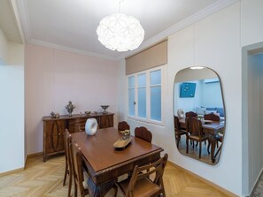 A dining room with a wooden table, chairs, a decorative vase, and a hanging light fixture. - Ivelia Athens - Boutique Residence with Private Spa (Athina)