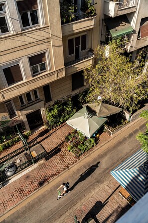 Vista aérea de uma rua com uma fileira de vasos de plantas e um guarda-chuva verde na calçada.
