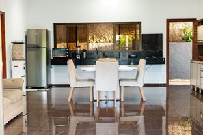 A modern kitchen with a dining area, a refrigerator, and a view through a window.