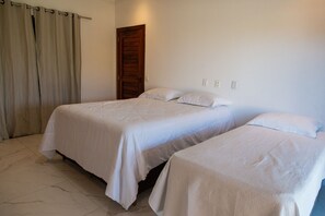A bedroom with two beds, a wooden door, and a curtain. - Casa 2 suites-piscina priv-Picos161m (Icapuí)