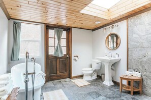 Une salle de bain avec une baignoire, des toilettes, un lavabo et une porte en bois.