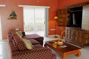 Ein Wohnzimmer mit einer Sofagarnitur, einem Couchtisch, einem Fernseher und einer Lampe.