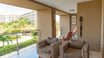 Uma varanda com móveis de vime, vista de um conjunto de edifícios e guarda-corpo.