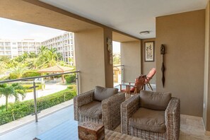 A balcony with wicker furniture, a view of a building complex, and a railing.