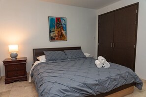 A bedroom with a bed, a nightstand, a lamp, a painting, and a wardrobe.