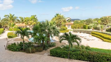 Um resort com piscina, palmeiras e jardins bem cuidados.