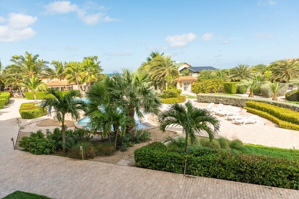 A resort with a pool, palm trees, and well-manicured gardens.