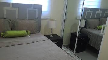 Une chambre d’hôtel avec un lit, des tables de chevet, une lampe et un miroir.