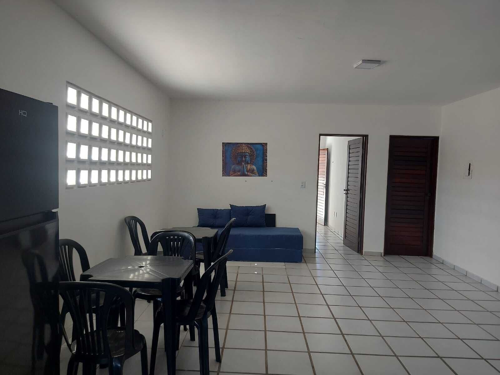 Um quarto com uma mesa de jantar, cadeiras, um sofá, um quadro e uma porta.