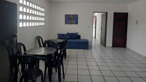Una habitación con una mesa de comedor, sillas, un sofá, un cuadro y una puerta.