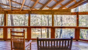 Une terrasse en bois offrant une vue sur une forêt et un plan d’eau.