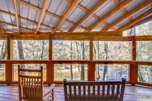 Eine Holzterrasse mit Blick auf einen Wald und ein Gewässer.