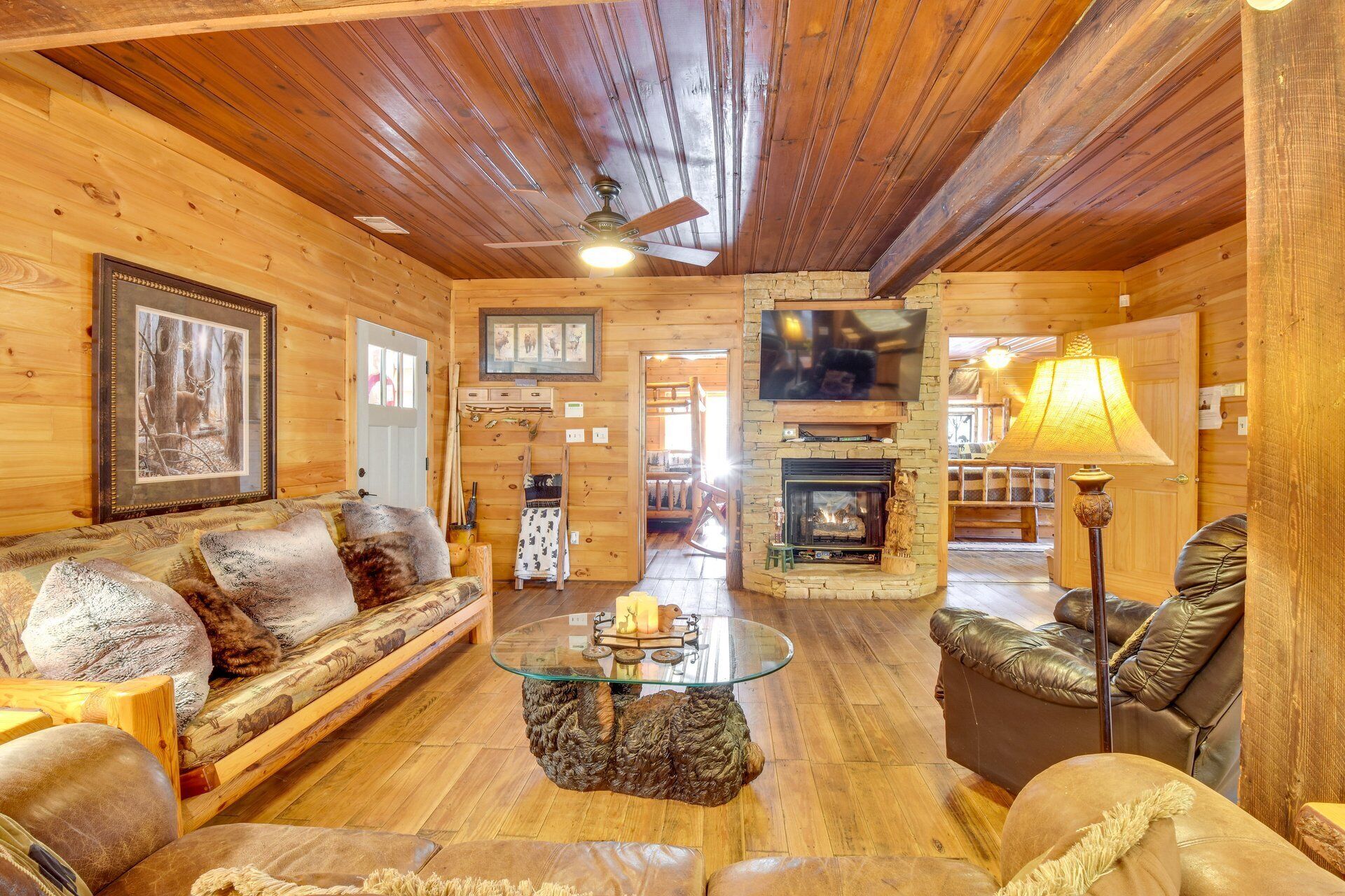 A cozy log cabin interior with a fireplace, wooden furniture, and a television.