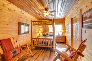 A log cabin interior with a wooden bed, a wooden bench, a ceiling fan, and a framed picture on the wall. - Riverfront Helen Cabin  Hot Tub + Fire Pit (Helen)
