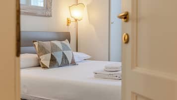 Ein Hotelzimmer mit einem ordentlich bezogenem Bett, einer Wandleuchte und einer Tür.