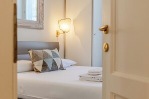 Ein Hotelzimmer mit einem ordentlich bezogenem Bett, einer Wandleuchte und einer Tür.