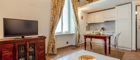 Un salon équipé d’un téléviseur, d’un meuble en bois et d’un coin repas avec une table et des chaises.