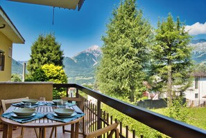 A dining table with plates and glasses, overlooking a mountainous landscape with trees and a clear sky. - Mountain Escape – Mountain View & Private Sauna (Cassina Valsassina)