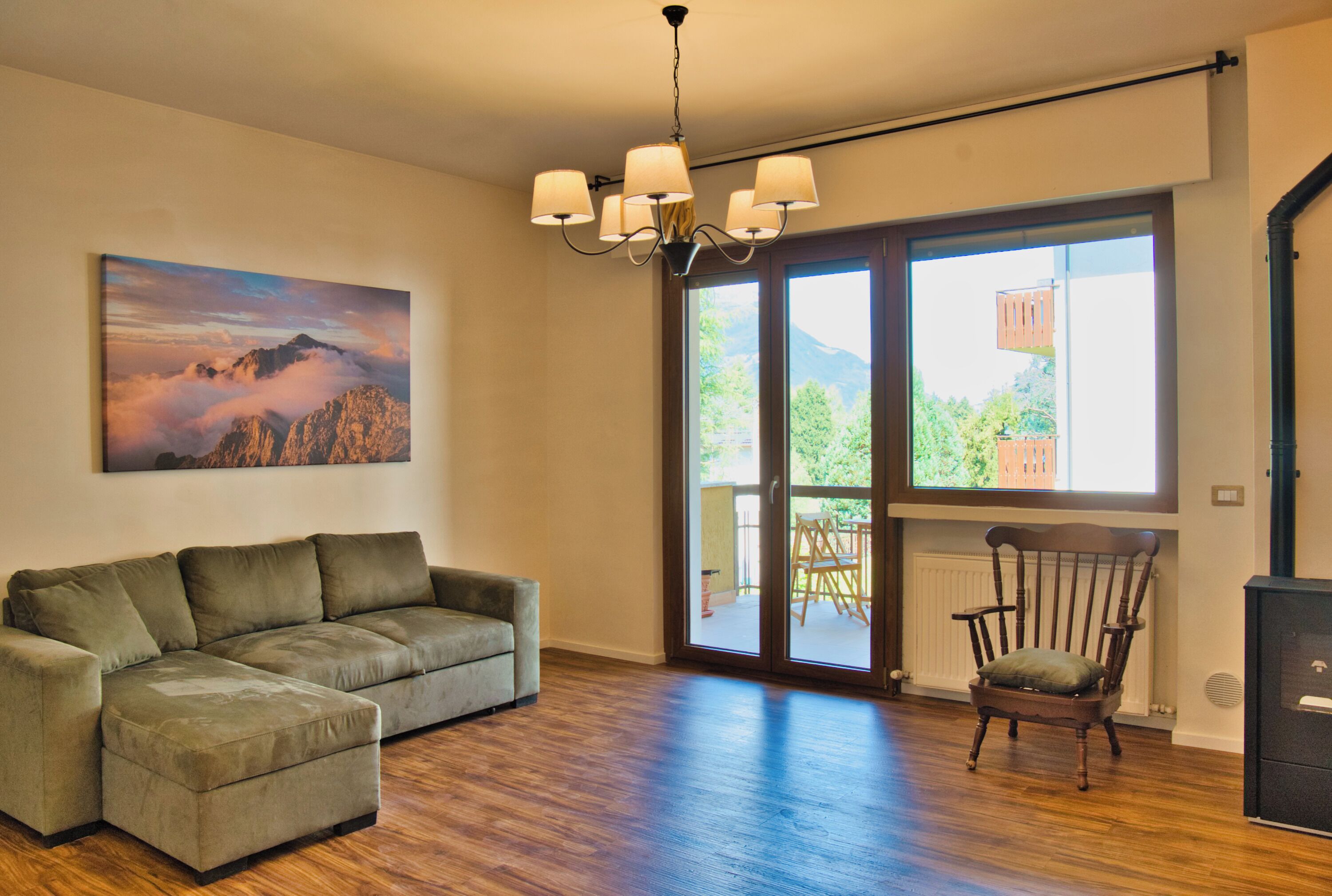A living room with a sofa, a chair, a painting, and a large window with a view.
