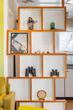 En hyllkonstruktion i trä med flera våningar, dekorerad med olika prydnadsföremål, inklusive figurer och ett inramat fotografi.
