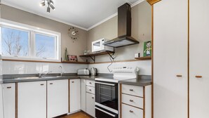 Une cuisine avec des armoires blanches, un four encastré, un four à micro-ondes et une fenêtre.