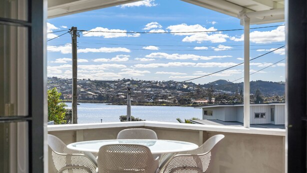 Un balcon avec une table et des chaises, donnant sur un lac et une ville.