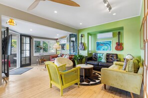 Un salon moderne avec un mur d’accent vert, un canapé, un fauteuil jaune et une table basse.
