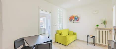 Una sala de estar moderna con una mesa de comedor, dos sillas, un sofá, un radiador y una obra de arte en la pared.