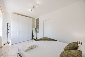 A bedroom with a bed, a coat rack, a wardrobe, and a mirror. - Cozy Nest [Vicino Ospedale Carle] (Cuneo)