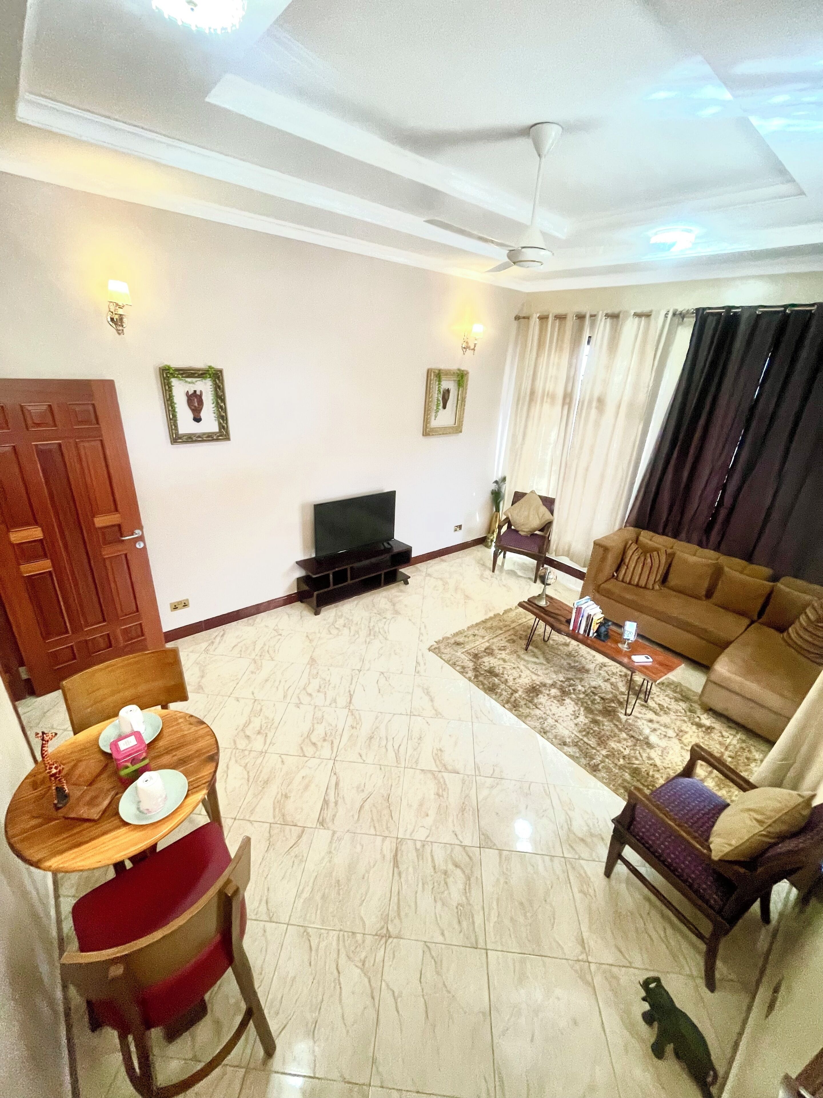 A living room with a television, sofa, coffee table, and a dining area with chairs and a table.