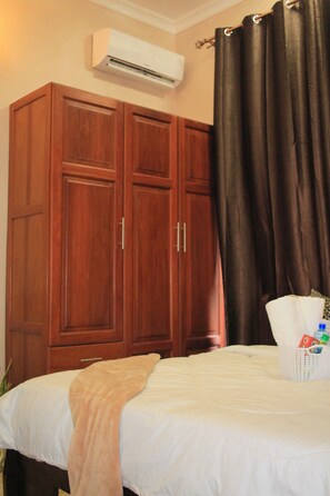 Une chambre à coucher comprenant un lit, une armoire et un appareil de climatisation.