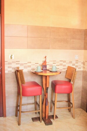 Un coin salon avec deux chaises en bois et une petite table, agrémenté d’une figurine décorative représentant une girafe.