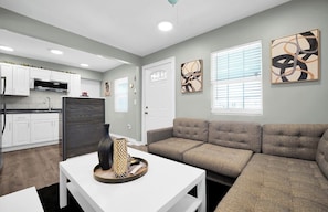 A modern living room with a sectional sofa, a white coffee table, and artwork on the walls.