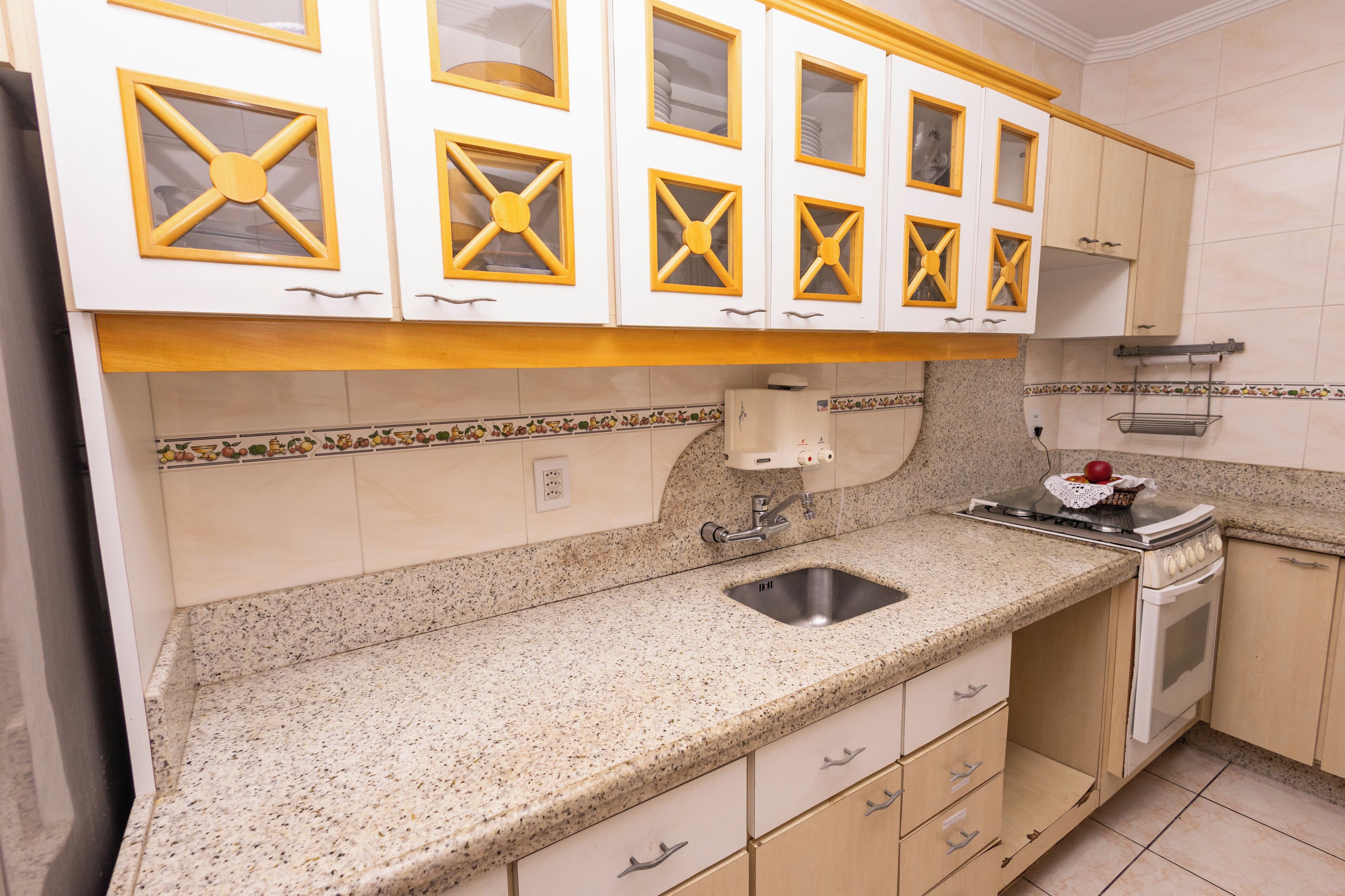 A kitchen with white cabinets, a granite countertop, a stainless steel sink, and a stove.