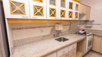 A kitchen with white cabinets, a granite countertop, a stainless steel sink, and a stove.