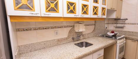 A kitchen with white cabinets, a granite countertop, a stainless steel sink, and a stove.