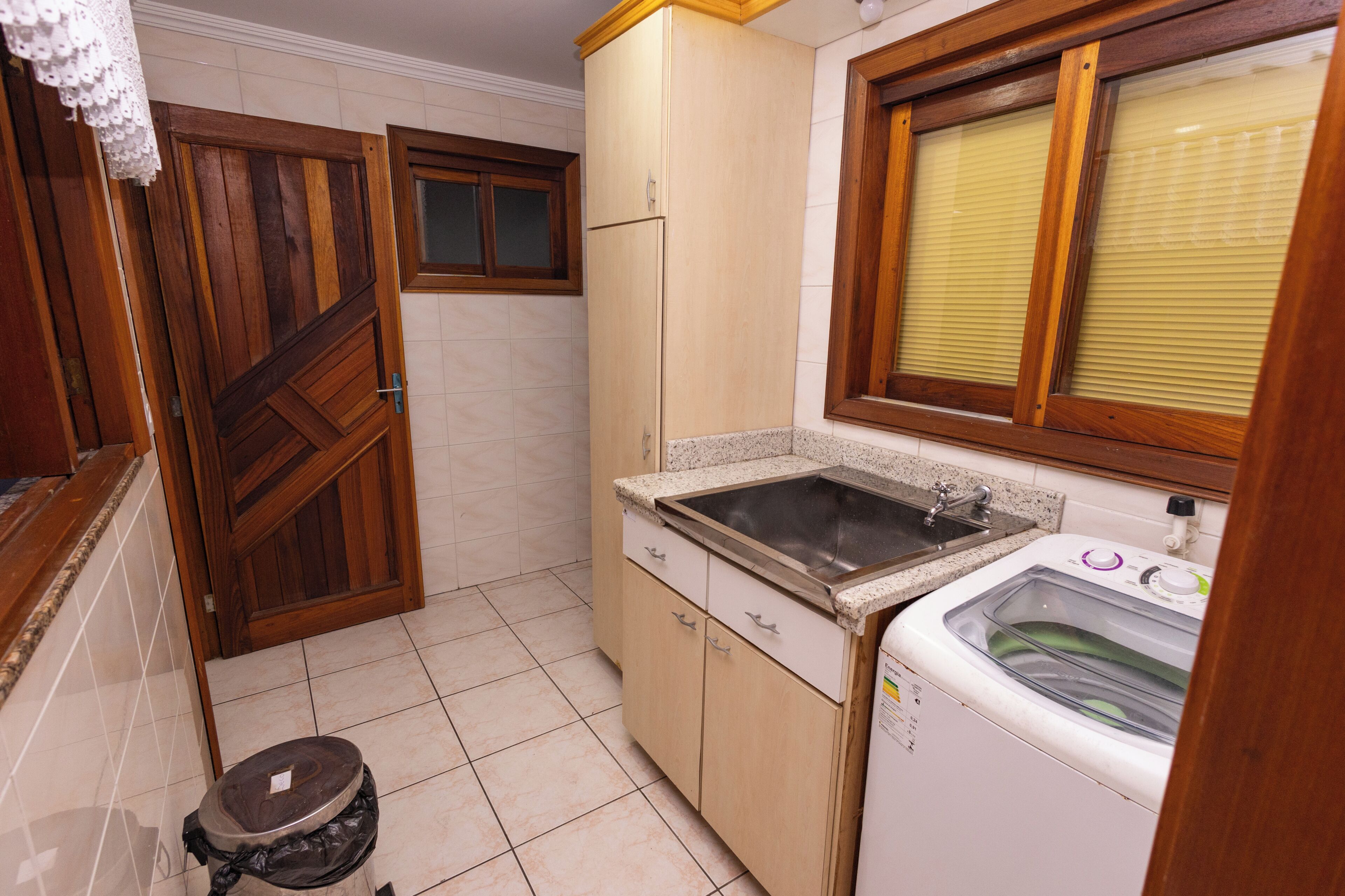 Une cuisine de taille réduite, équipée d’un lave-linge, d’un évier et de meubles de rangement en bois.