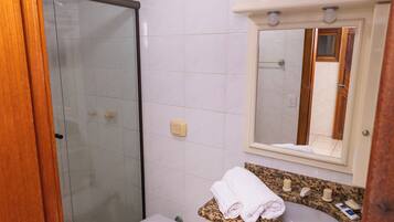 A bathroom with a toilet, sink, mirror, and shower.