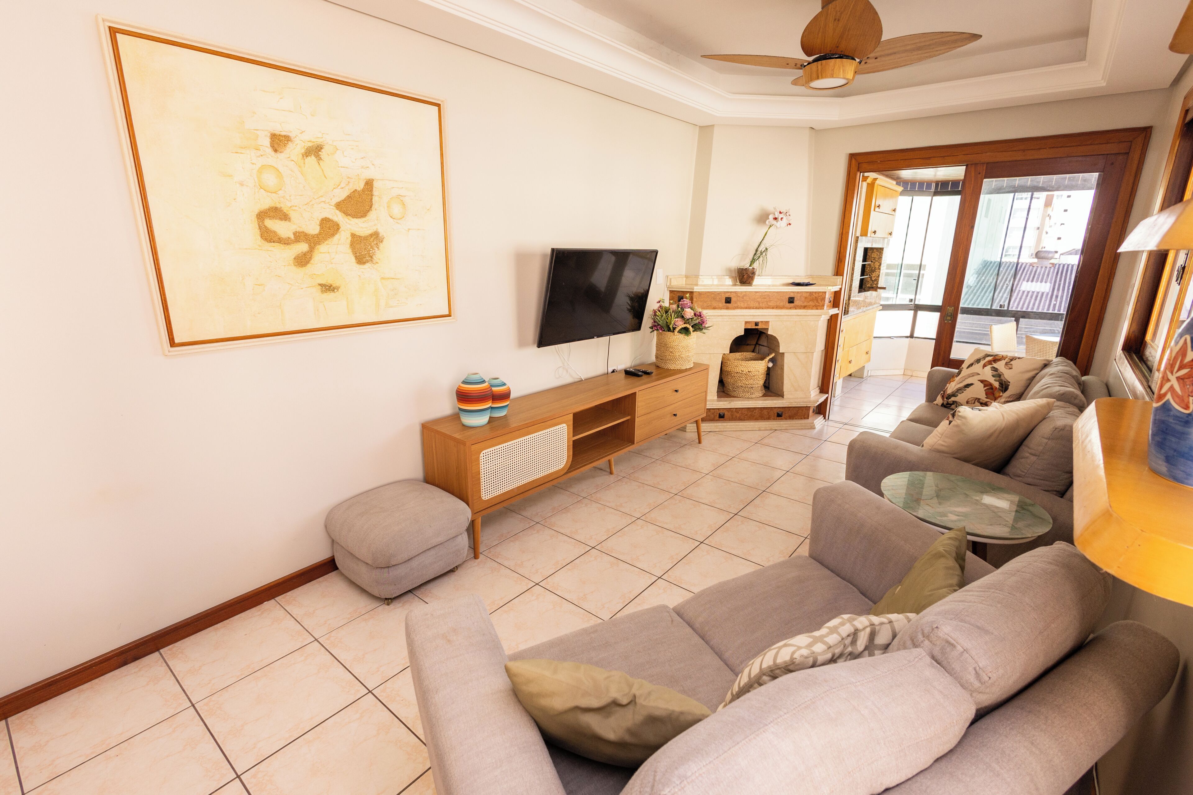 Una sala de estar con un sofá, un televisor, una chimenea y un balcón.
